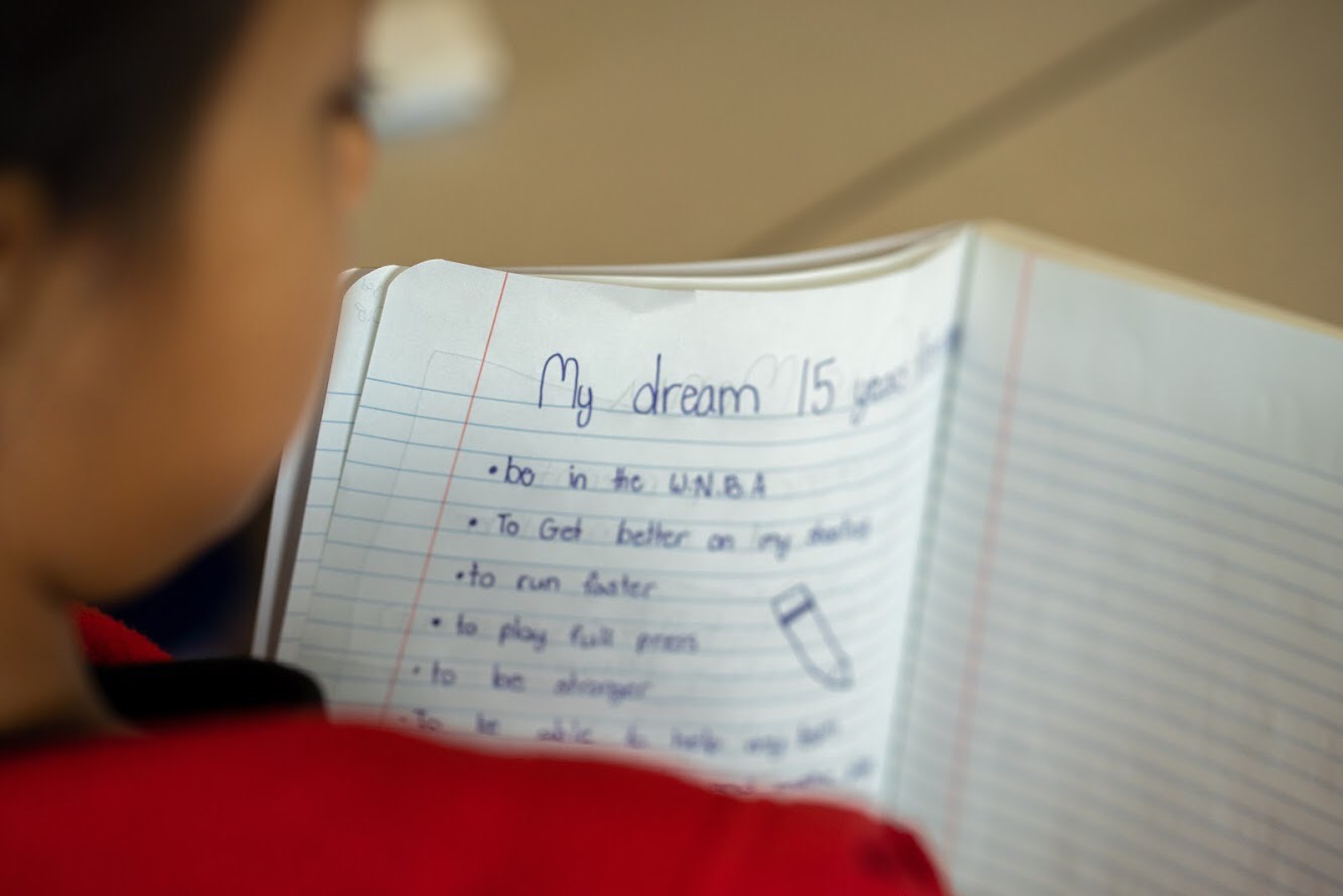 over a child's shoulder, a written list of goals and dreams